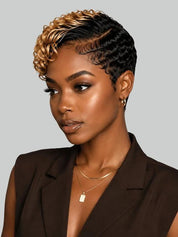 A woman with a short, styled micro-lobed haircut featuring dark brown to black roots and warm blonde highlights, wearing a dark brown blazer against a solid gray background.