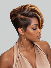 A woman with a short, styled pixie cut featuring dark brown roots and warm blonde highlights, wearing a beige halter top and large gold hoop earrings against a solid gray background.