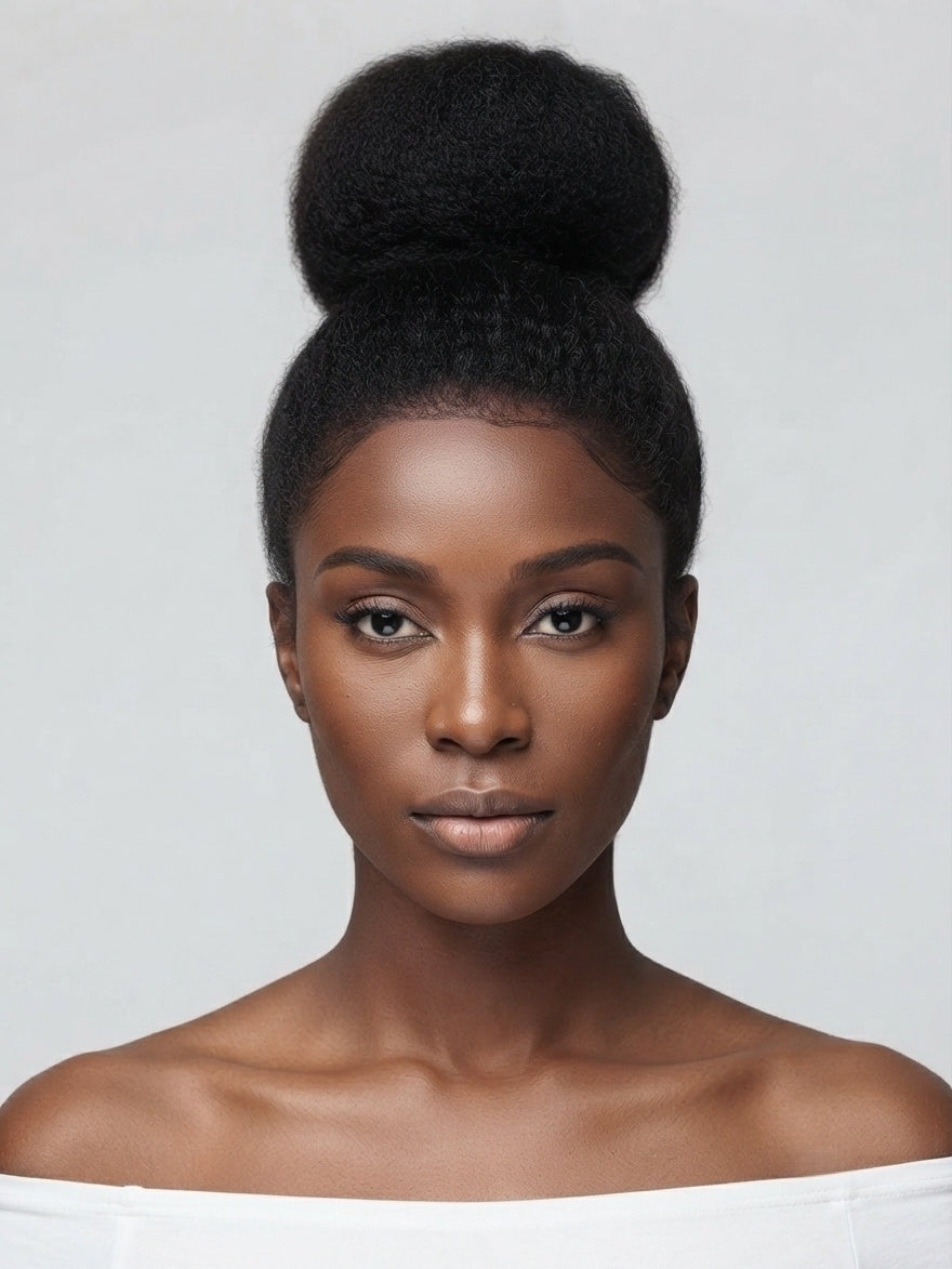 A woman with a high, voluminous black hair bun, wearing a white off-the-shoulder top against a light gray studio background.