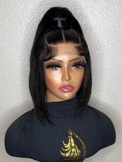 A black lace front wig with a high ponytail and bangs, displayed on a mannequin bust wearing a black turtleneck with a gold graphic.