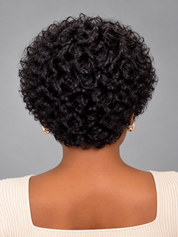 Rear view of a person with a short, tightly curled black wig or hairpiece against a plain gray studio background.