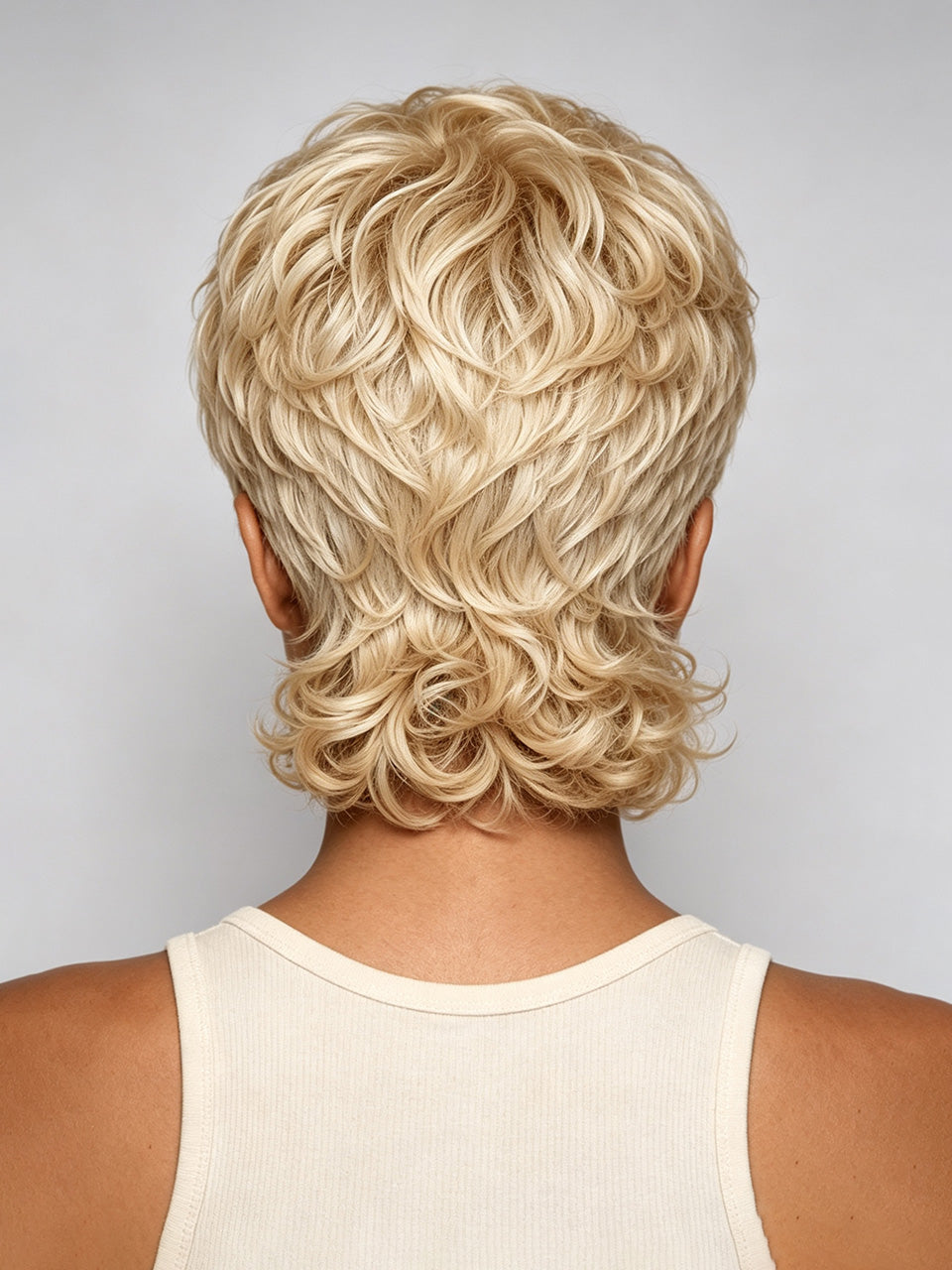 Back view of a person wearing a short, layered blonde wig with textured curls, shown against a light gray studio background.