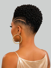 A woman shown from the back wearing a short, textured, high-contrast fade haircut with gold hoop earrings and a champagne satin top, set against a solid gray background.