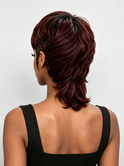 A woman shown from the back wearing a short layered wig with deep burgundy and dark brown tones, paired with a black ribbed tank top against a light gray studio background.