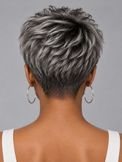 Back view of a person with a short, layered pixie cut featuring mixed silver-gray and dark brown hair, wearing large gold hoop earrings and a white tank top against a solid gray background.