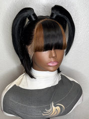A black wig with two high pigtails and straight bangs, styled on a mannequin head against a light textured wall.