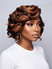 A woman wearing a short, layered wig with dark brown and warm caramel-blonde highlights, styled in soft curls, against a light gray studio background.