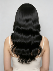 Long, straight black hair with soft waves, shown from the back on a model wearing a cream-colored spaghetti strap top against a light gray background.