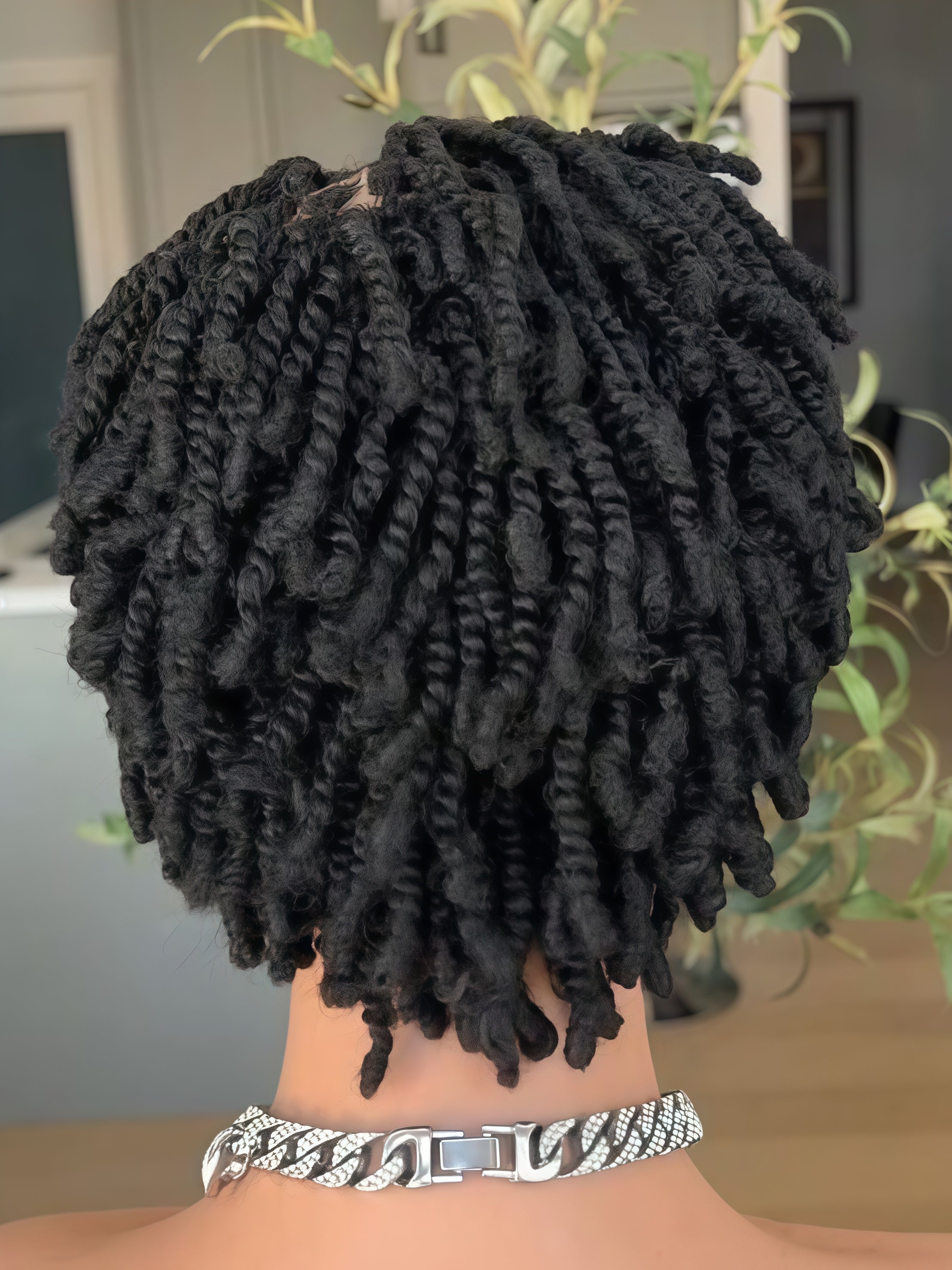 Black twisted locs hair extensions shown from the back on a mannequin head, featuring a chunky silver Cuban link chain necklace.