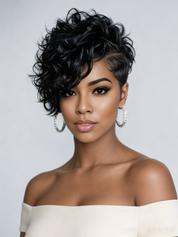 A woman with a short, voluminous, curly black wig wearing a cream off-the-shoulder top and silver hoop earrings, photographed against a light gray studio background.