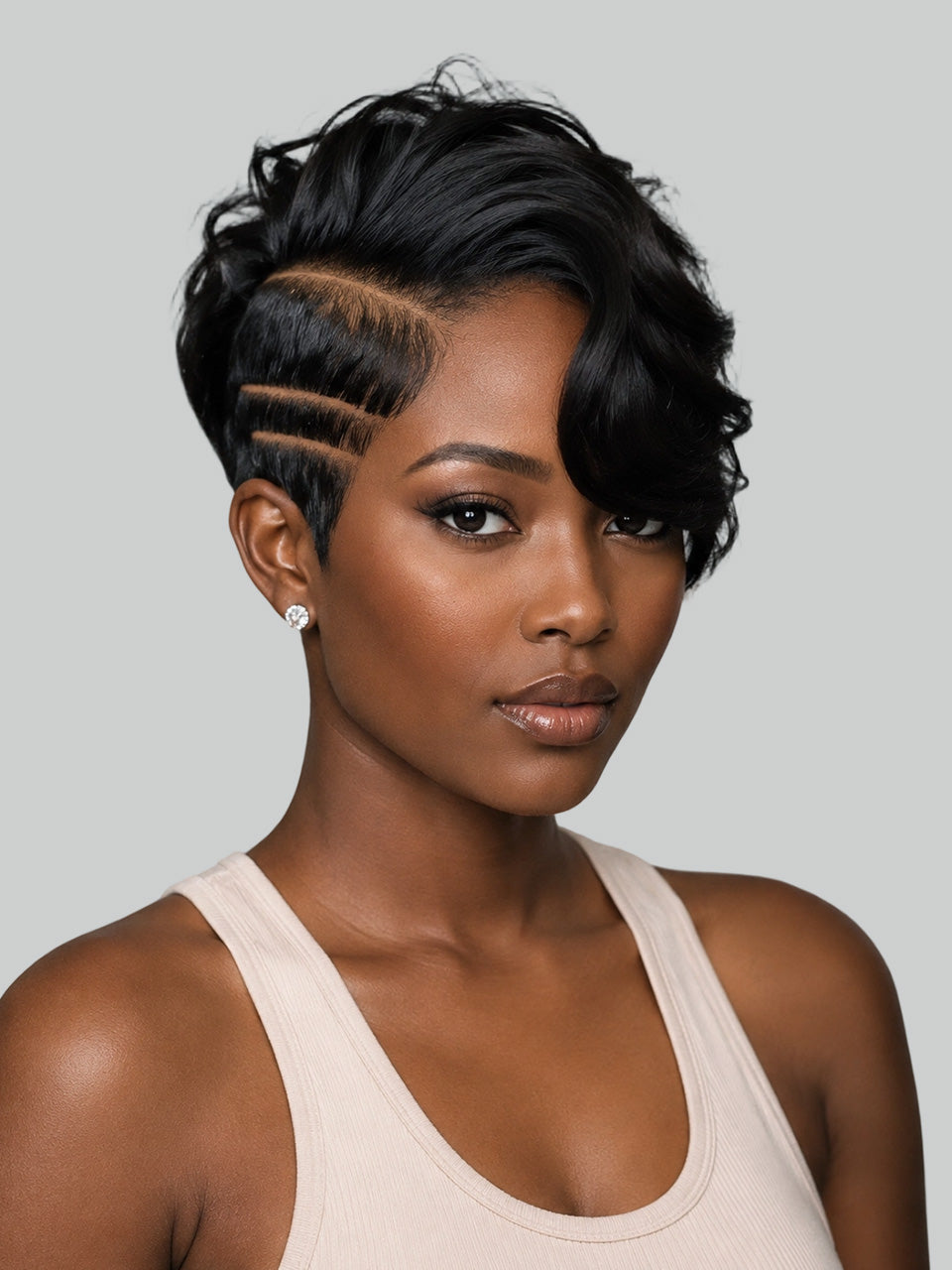 A woman with a short, styled black wig featuring side-combed, layered waves and geometric haircuts on the side, wearing a light beige ribbed tank top against a solid gray background.