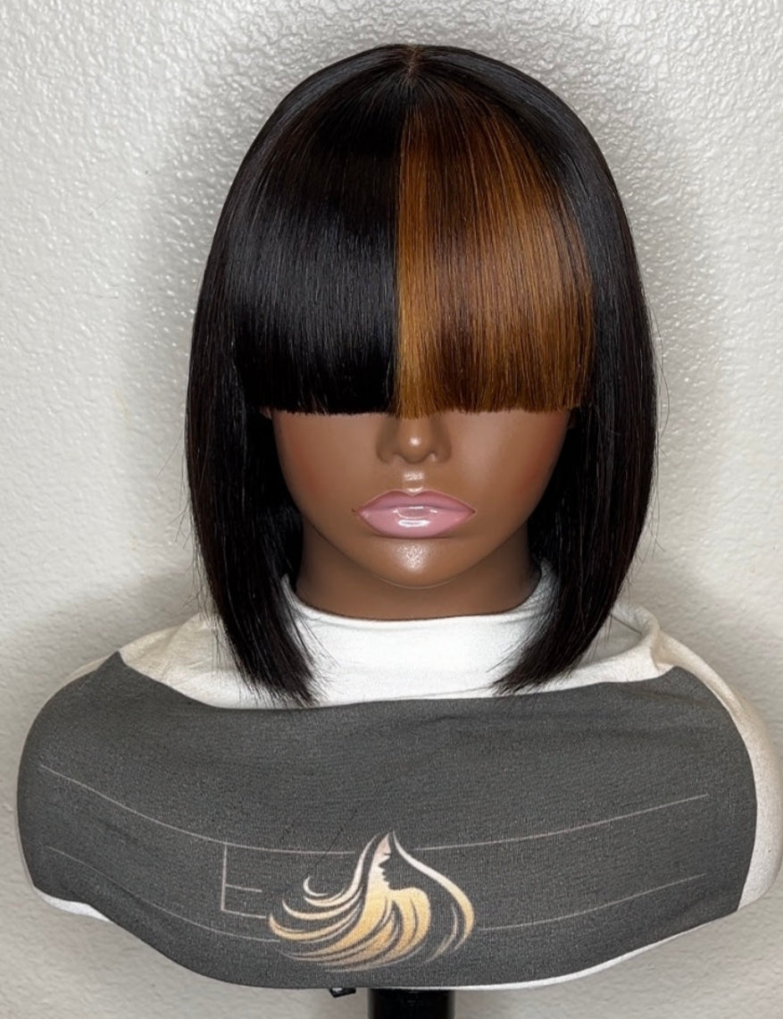 A straight bob wig with a center part, featuring a dark black side and a warm brown center section, displayed on a mannequin head with a gray salon cape.