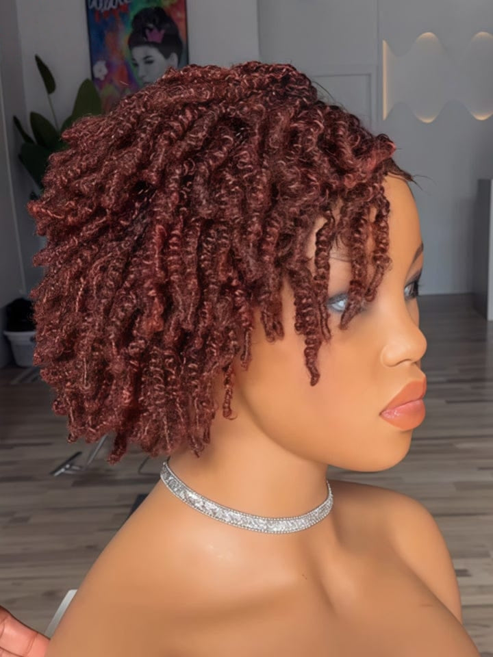 A short, curly wig displayed on a mannequin head in profile, featuring tight, glossy ringlets in a deep auburn reddish-brown color. The mannequin is shown indoors with a blurred background of a room.
