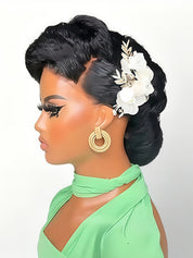 A mannequin bust shown in side profile wearing a mint green high-neck top, with dramatic black hair styled in an updo and decorated with white flowers, plus large gold hoop earrings, against a plain light background.