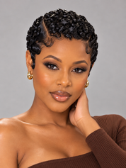 A close-up portrait of a woman with short, tightly curled black hair styled in a braided or twisted updo, wearing gold hoop earrings and a brown ribbed strapless top against a plain gray studio background.