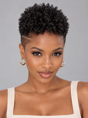 A close-up portrait of a woman with a short, curly black afro hairstyle and a clean side shave, wearing gold hoop earrings and a cream ribbed tank top against a solid gray background.