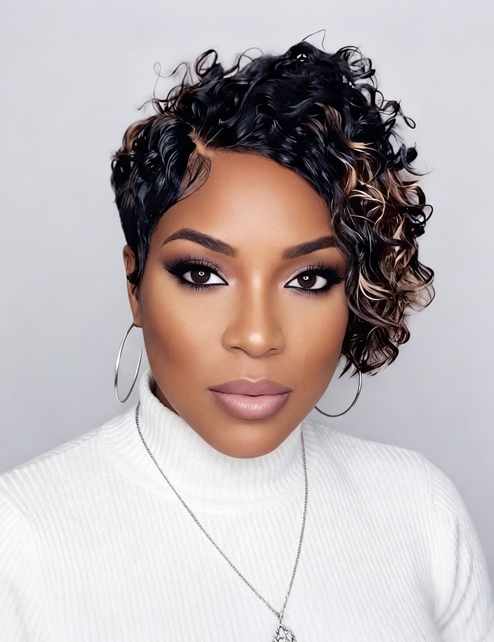 A close-up portrait of a woman with a short, curly wig. The wig features a dark black base with warm caramel and light brown highlights, styled in tight, defined curls.