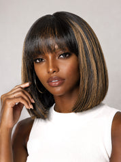 A woman modeling a short, straight bob wig with straight bangs. The wig features a dark brown base with highlighted warm brown and blonde streaks.