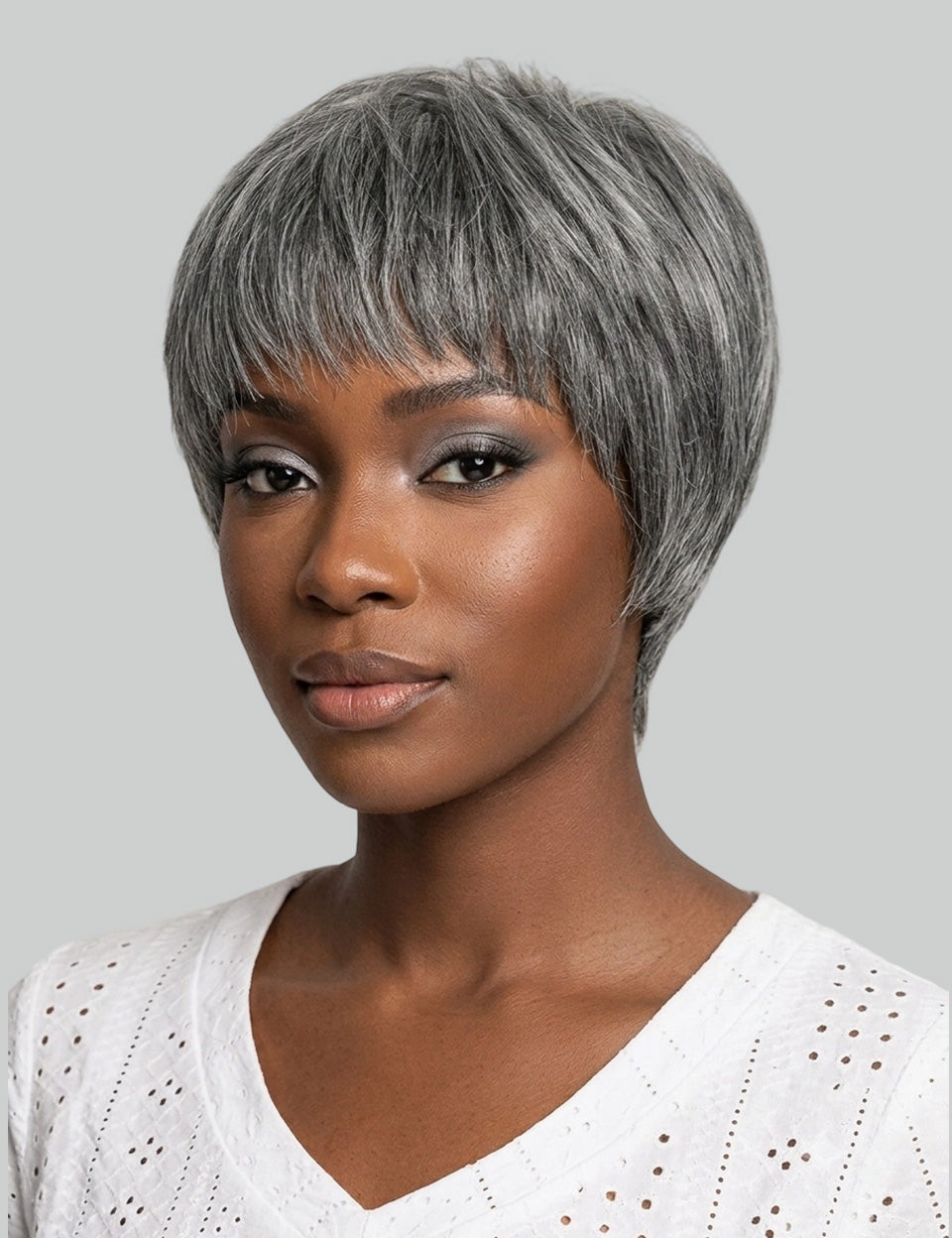A woman wearing a short, layered gray wig with side-swept bangs, shown against a plain light gray background.