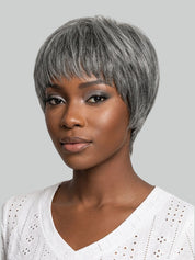 A woman wearing a short, layered gray wig with side-swept bangs, shown against a plain light gray background.