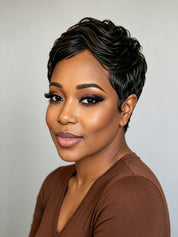 A close-up portrait of a woman with short, styled black hair wearing a brown V-neck top against a plain light gray background.