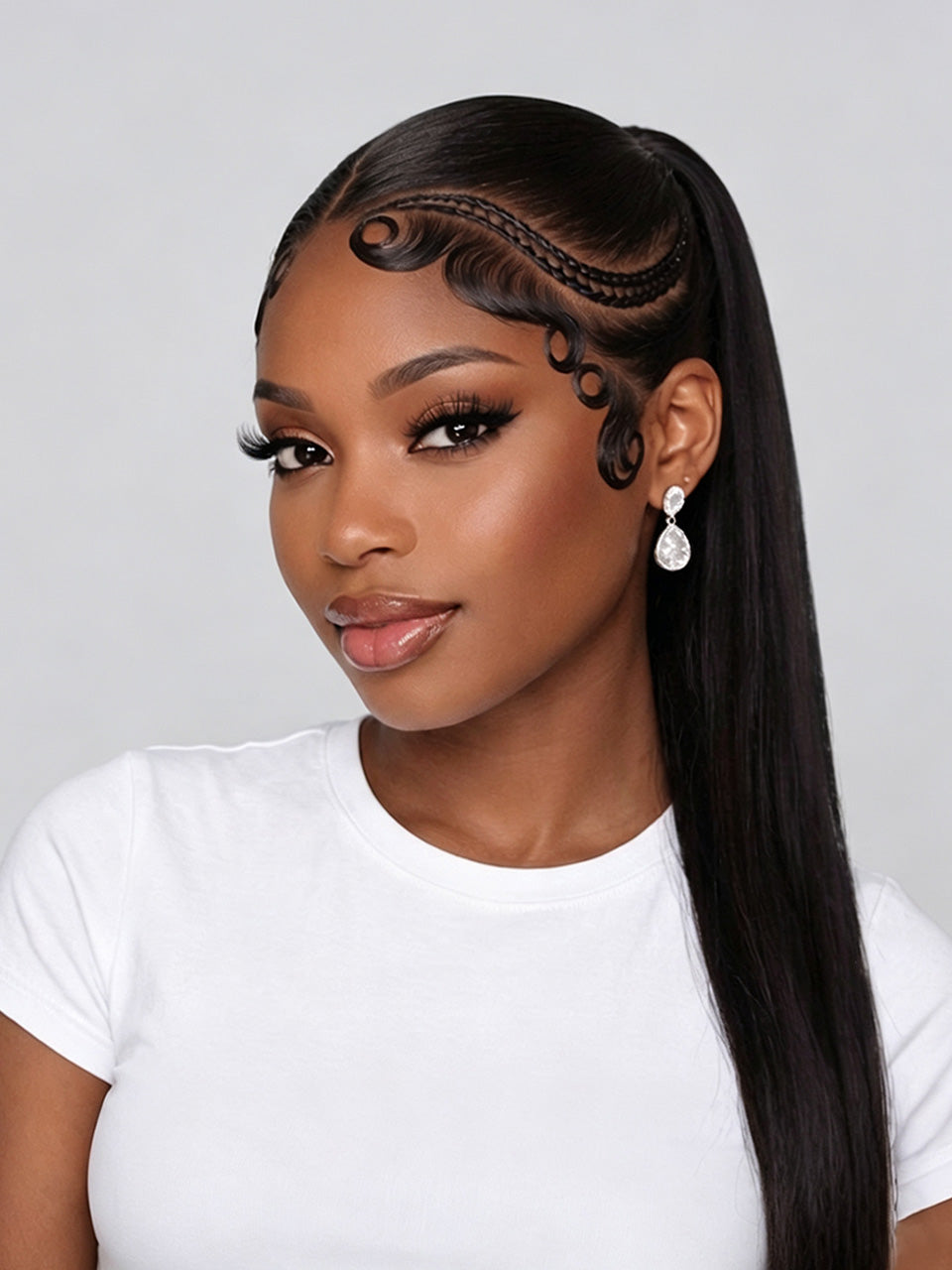 A woman with long, straight black hair styled in a high ponytail with decorative braided detailing along the hairline, wearing a white t-shirt and dangling earrings against a light gray background.