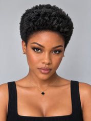 A close-up portrait of a woman with short, curly black hair, wearing a black ribbed tank top, a delicate gold necklace with a black clover pendant, and small gold stud earrings, set against a solid gray background.