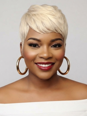 A smiling woman with a short, layered platinum blonde wig, wearing large gold hoop earrings and a white off-the-shoulder top against a light gray background.