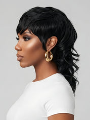 Left side profile of a model wearing a black wolf cut wig with textured bangs and long, layered body waves. The silhouette highlights the volume at the crown and the feathered layers framing the face, paired with gold hoop earrings.