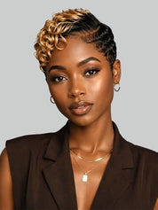 A woman with a short, styled curly wig in black and blonde highlights, wearing a dark brown sleeveless blazer and gold jewelry against a solid gray background.