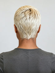 Back view of a person with a short, layered, textured blonde hairstyle wearing a dark gray t-shirt against a light gray background.