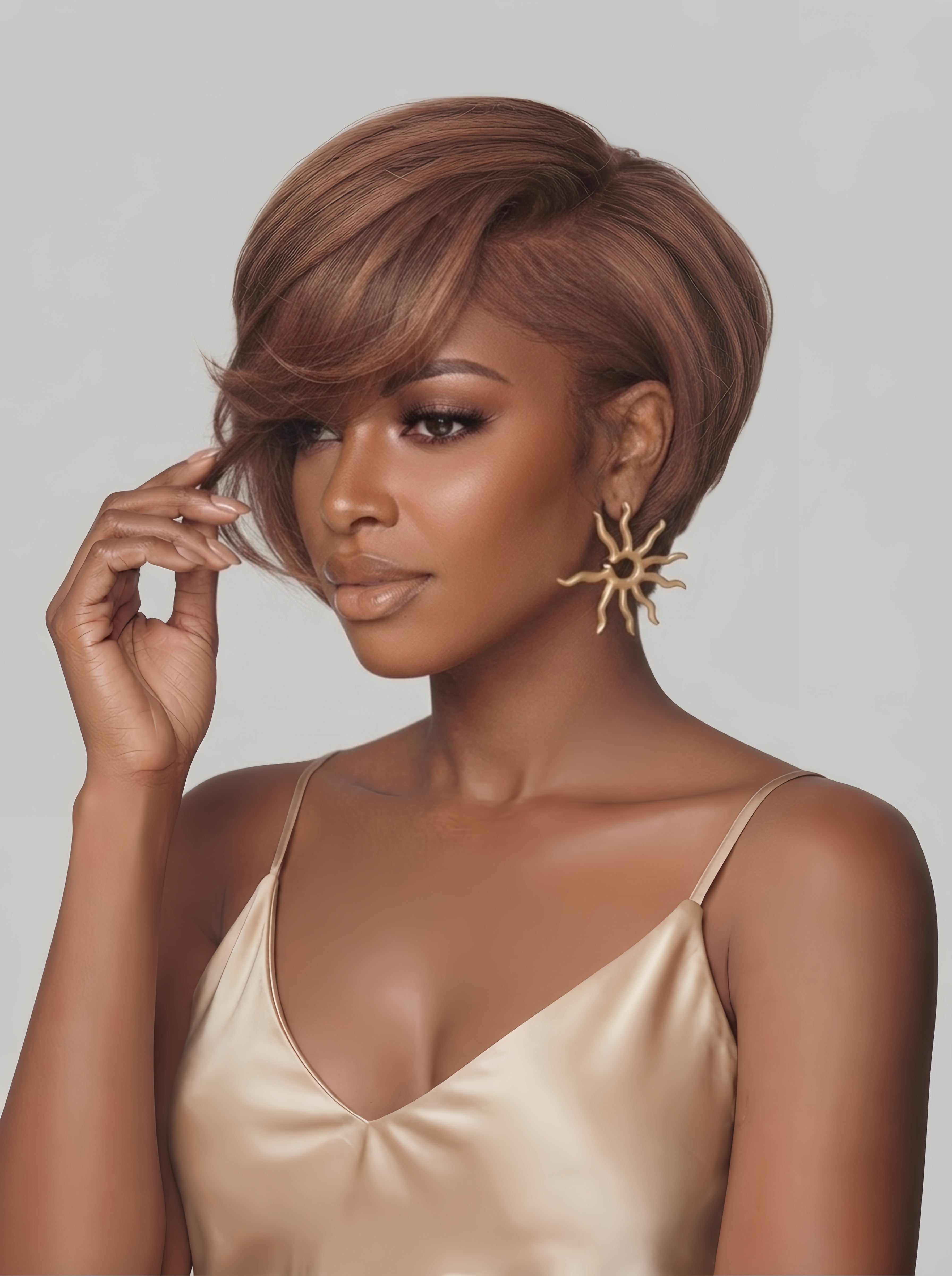 Side angled view of a woman wearing a sleek light brown pixie wig with side-swept bangs. The model gently touches the layered fringe, highlighting the smooth texture and natural flow of the straight short hair.