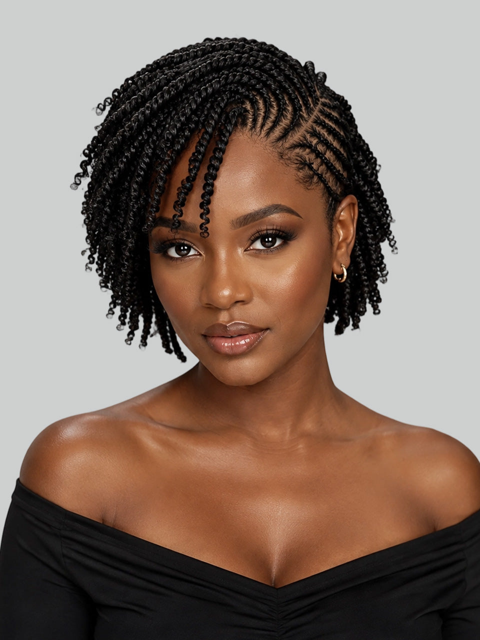 A woman with short, curly black box braids wearing a black off-the-shoulder top, shown against a solid gray background.