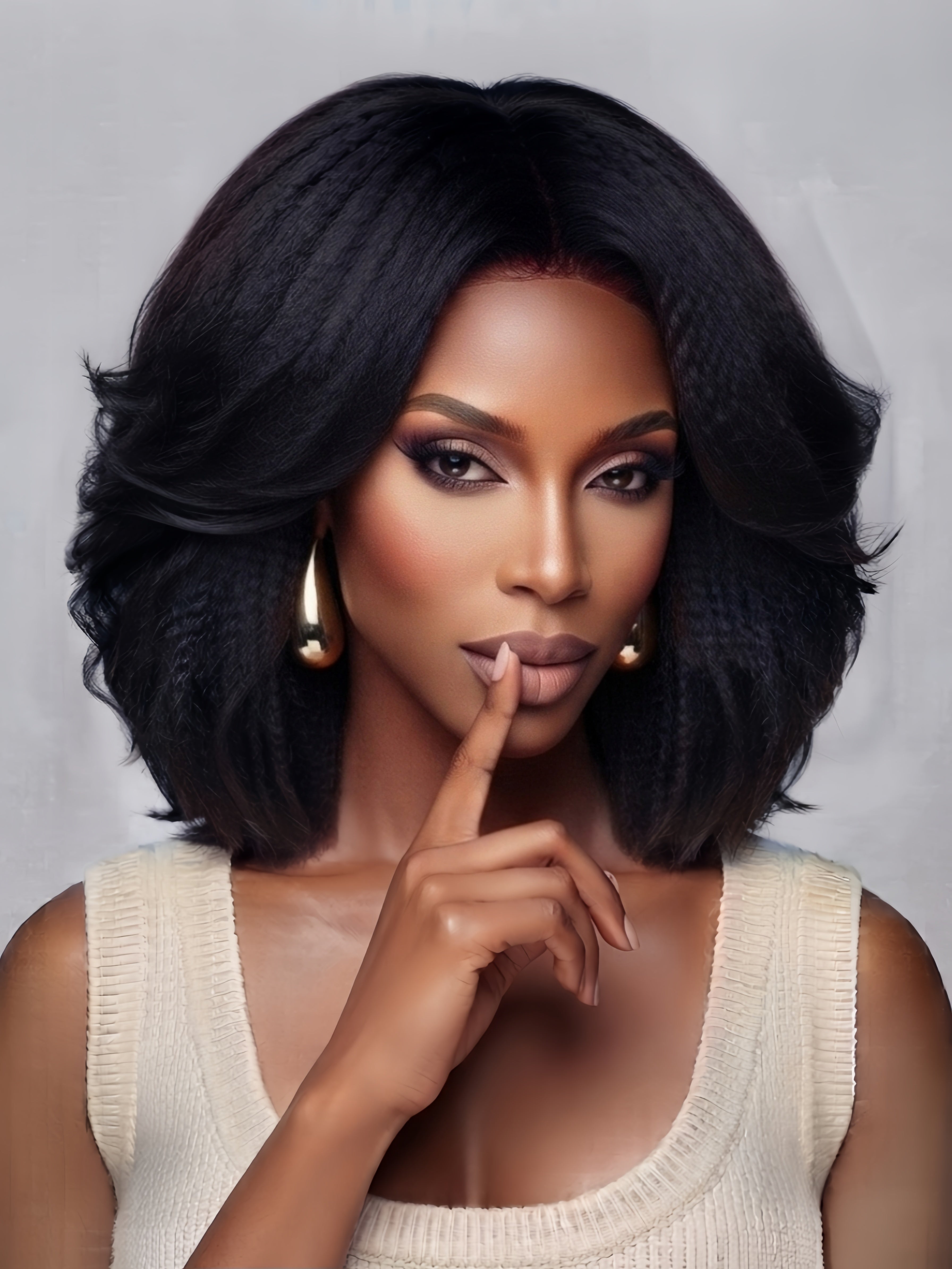 Frontal close-up of a woman wearing a black shoulder-length wig with soft, bouncy waves and a center part. The voluminous curls frame the face elegantly, complemented by bold smoky eye makeup and gold teardrop earrings for a glamorous, confident look.