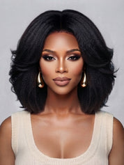 Frontal portrait of a woman in a black center-parted wave wig, emphasizing the realistic lace front hairline and symmetrical curl pattern. The full-bodied style and polished finish make it ideal for both casual and formal occasions, enhanced by minimalist gold hoop earrings.