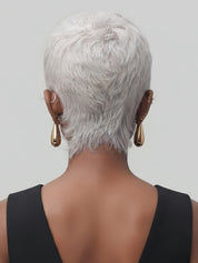 Rear view of a person with short, textured silver hair wearing a black sleeveless top and gold teardrop earrings against a solid gray background.