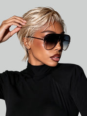 Side view of a woman wearing a golden blonde pixie cut wig with a slicked-back wet look. She is touching her short hair, showing the natural 13x4 lace front hairline and gold hoop earrings.