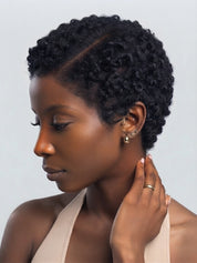 Side profile of a woman wearing a short curly lace frontal wig. Highlights the defined side parting space on the 13x4 lace and the rounded silhouette of the afro texture pixie cut.