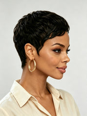 Side profile of a model in a short black wavy pixie wig, highlighting the side-swept bangs and layered texture around the ear. The soft curls frame the face elegantly, demonstrating a chic and low-maintenance style.