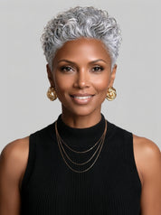 Frontal portrait of a woman wearing a silver grey short curly pixie wig with defined curl pattern. The symmetrical layers and natural parting create a balanced look, ideal for those seeking a stylish and low-maintenance short hairstyle.