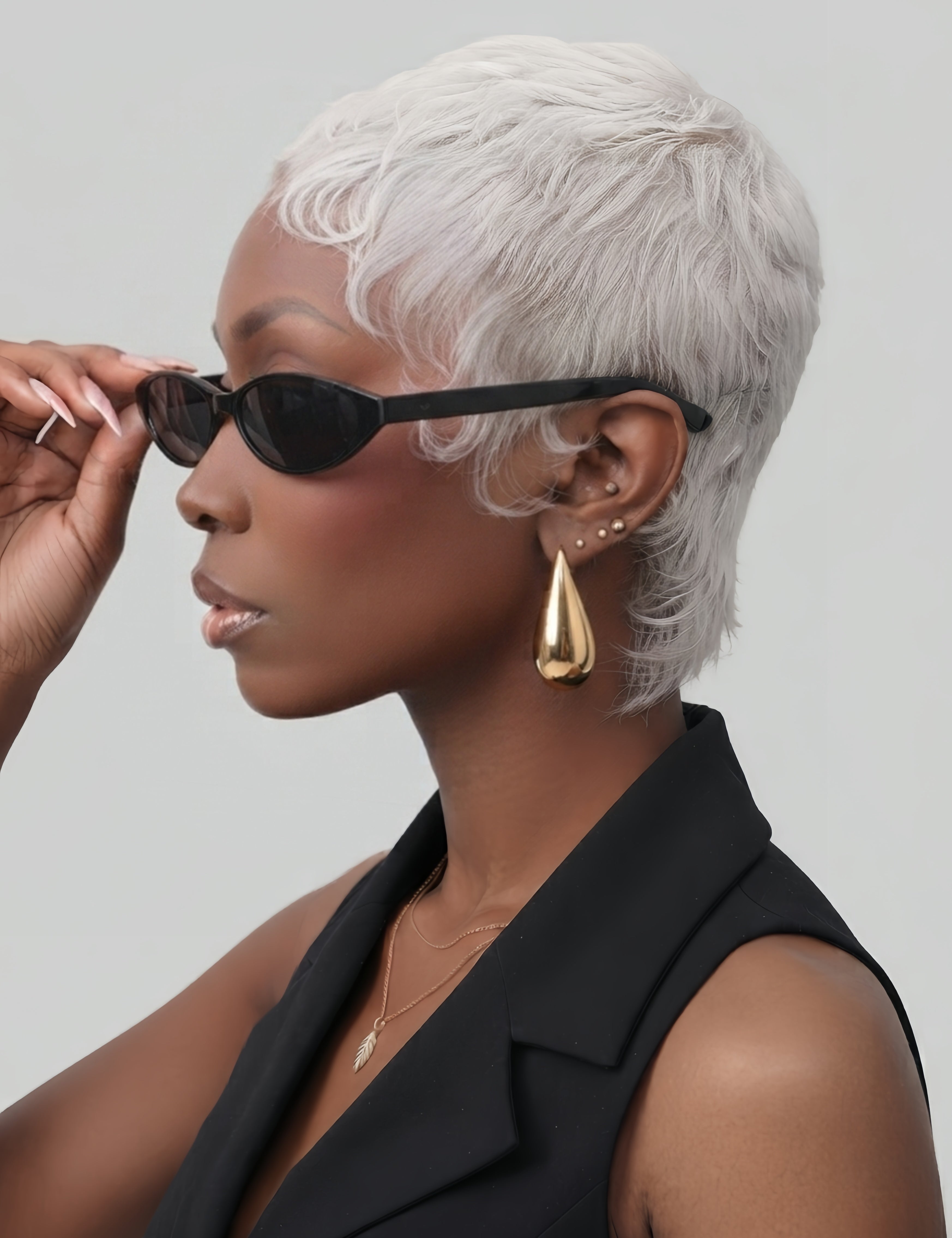 Woman wearing 18K gold-plated stainless steel water drop earrings with high polish finish. The minimalist teardrop design complements her short ICE SILVER pixie wig and chic black sleeveless top, perfect for modern fashion styling.