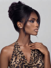 Side profile of a model showing the texture and volume of a messy high bun human hair wig. The sleek black hair is pulled back, highlighting the realistic silhouette and ear tabs.