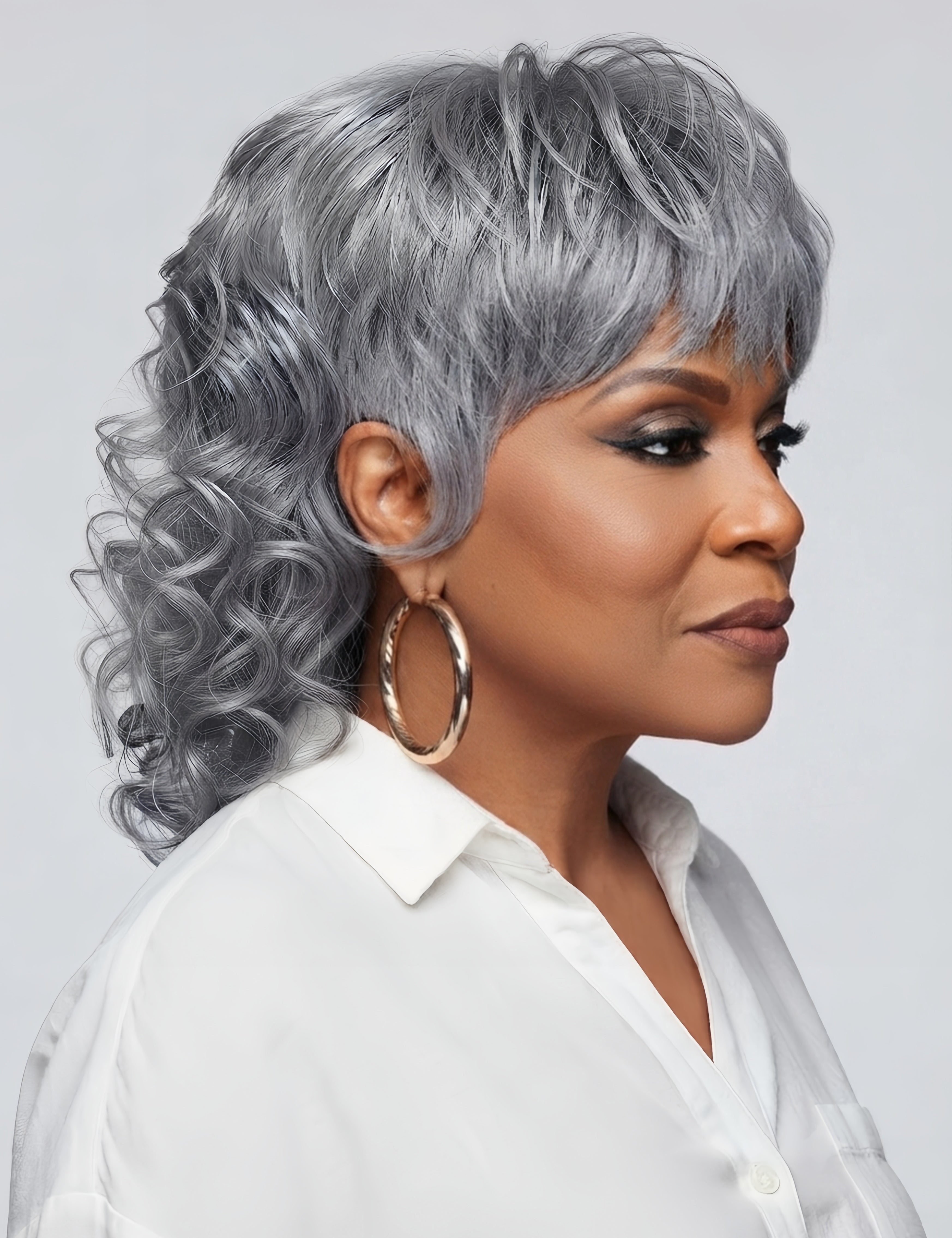 Right side profile of a model in a short grey curly wig, revealing the feathered layers and side-swept bangs. The silhouette emphasizes the modern mullet shape with a fluffy texture around the ears and neck, suitable for a bold and stylish look.