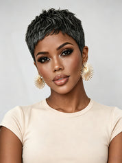 Frontal close-up of a woman wearing a salt and pepper pixie wig with textured, spiky layers. The short cut frames the face sharply, highlighting bold makeup and gold sunburst earrings for a modern, confident look.