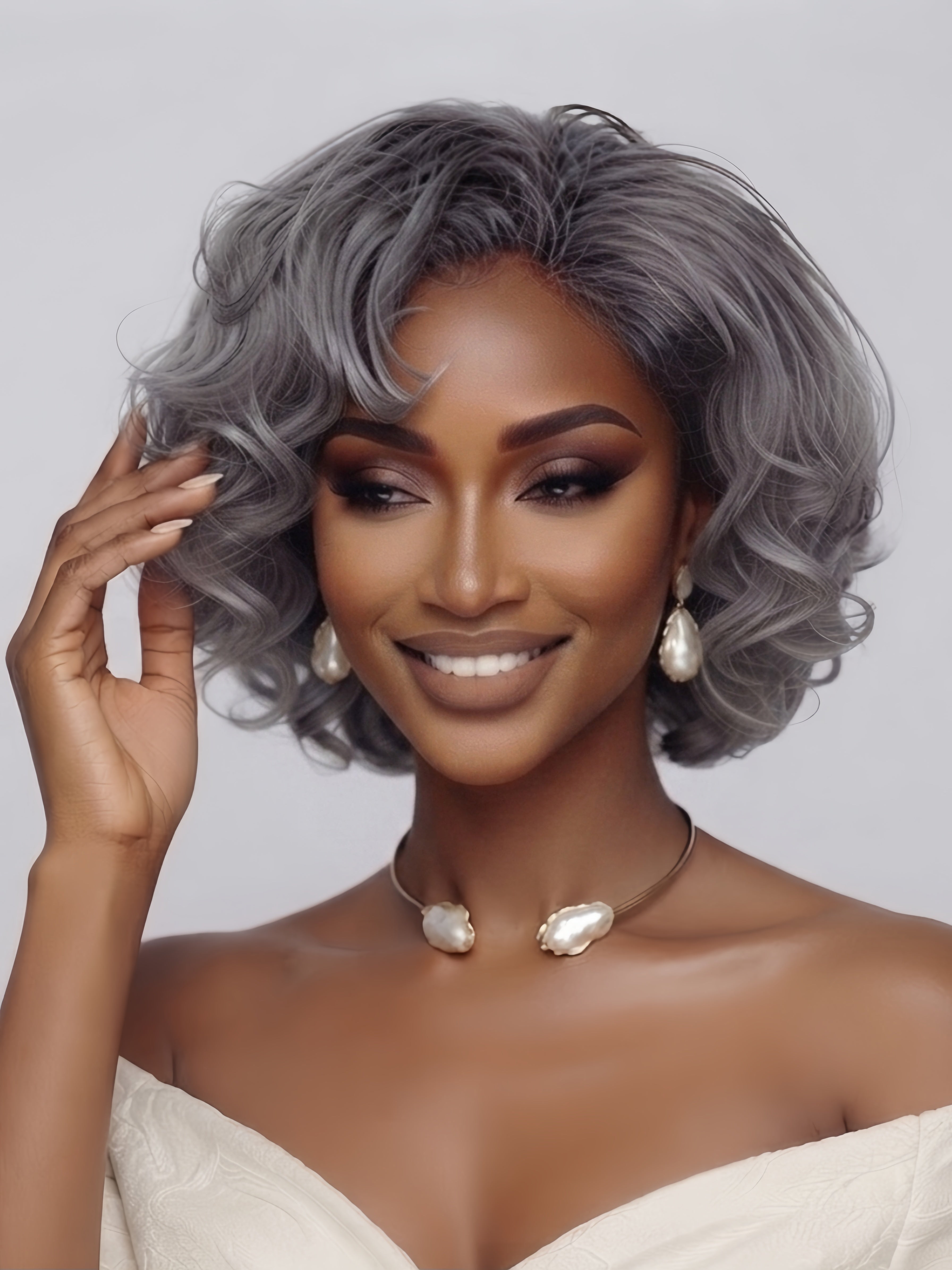 Front angled view of a woman wearing a silver grey short curly bob wig with side-swept bangs. The model gently touches the soft, voluminous waves, highlighting the natural movement and fluffy texture of the grey hair.