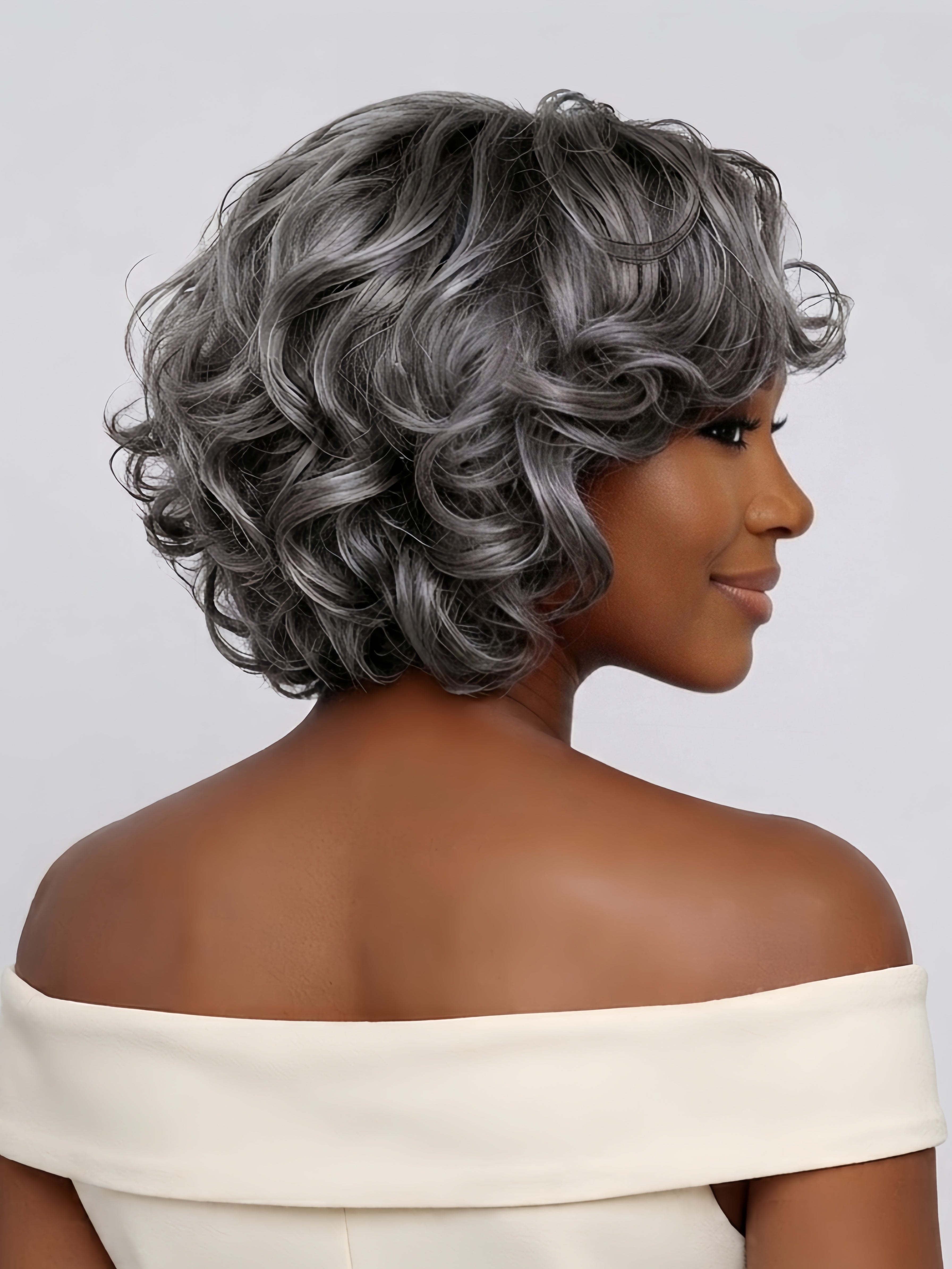 Back view displaying the stacked layers and rich volume at the nape of the short grey curly wig. This angle reveals the intricate curl definition from root to tip and the tapered cut that creates a full, rounded silhouette.