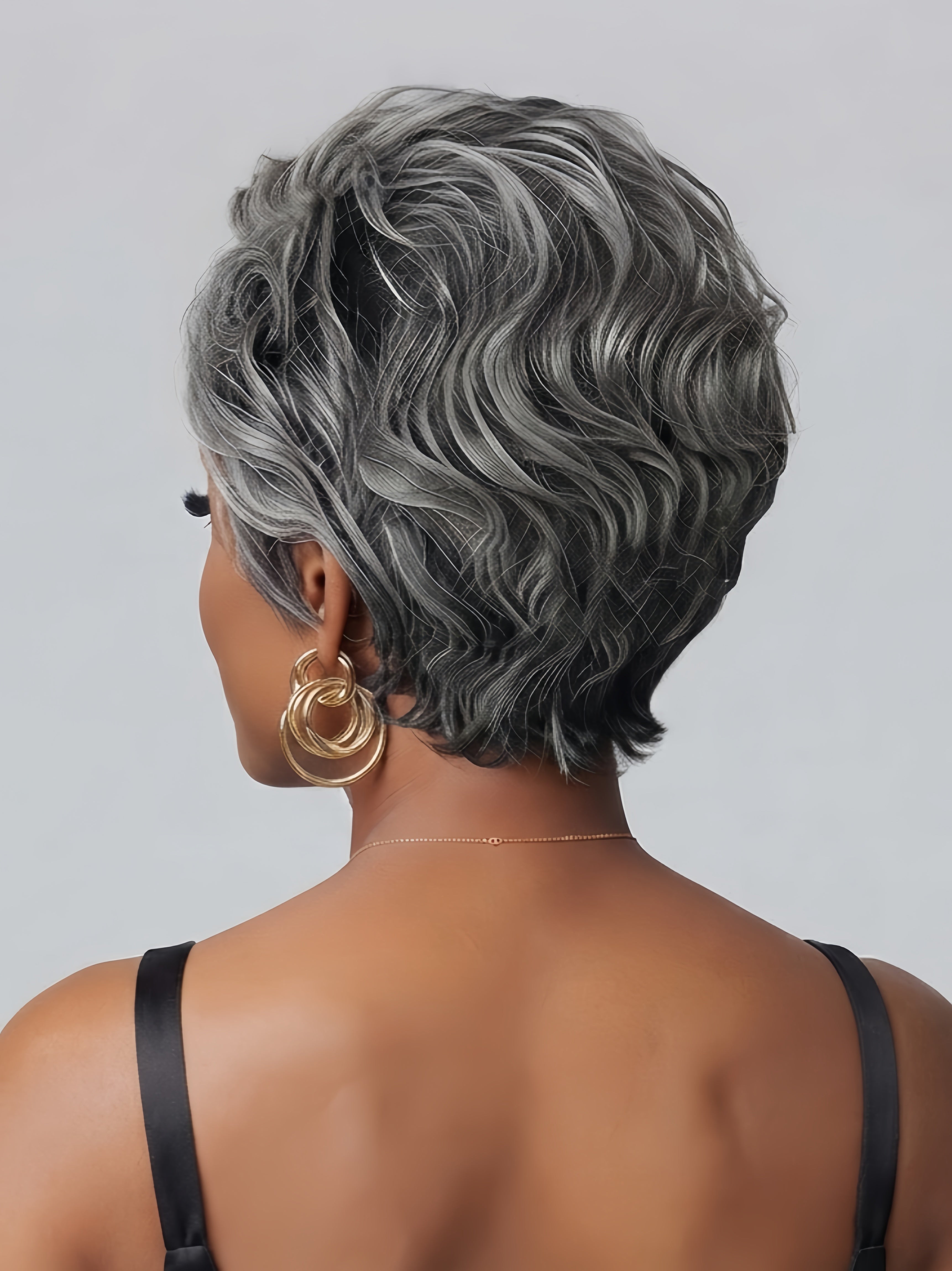 Back view of the short grey curly wig showcasing the layered cut and bouncy spiral curls at the nape. The hair transitions smoothly from darker roots to lighter ends, highlighting the realistic texture and volume suitable for everyday wear.