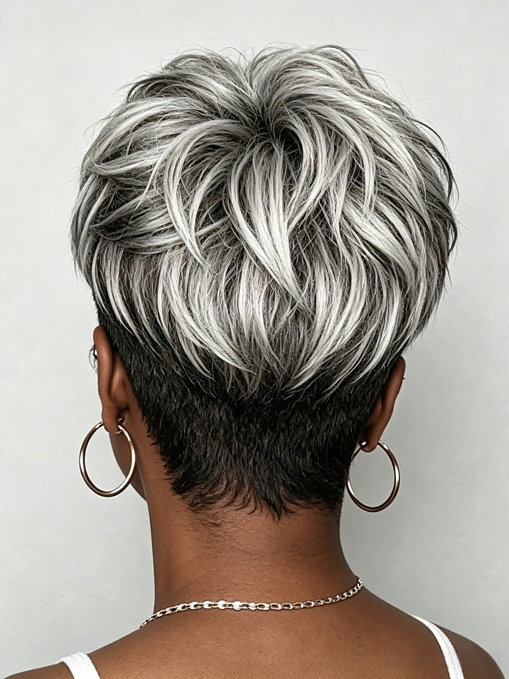Back view of a short layered hair topper featuring a trendy salt-and-pepper grey highlight mix. The tapered nape cut blends naturally with bio hair, showcasing the realistic texture and volume of the pixie style."