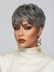 Three-quarter portrait of a woman in a chic salt and pepper pixie cut topper, featuring a soft side-swept fringe. The textured top adds height and dimension, while her bold terracotta eye makeup and matte brown lips enhance her features. Large gold hoop earrings with pearl accents complete the elegant and confident look.