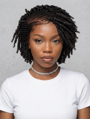 A woman with short, styled black twisted braids or box braids wearing a white t-shirt and a sparkling silver choker necklace, shown from the chest up against a neutral gray textured background.